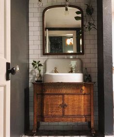 a bathroom sink sitting under a mirror on top of a wooden cabinet next to a doorway