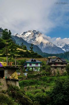 the mountains are covered with snow in the distance, and houses on the hillside below