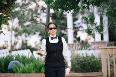 a woman dressed in black and white is walking down the street with sunglasses on her head