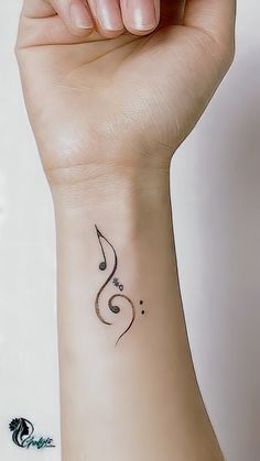 a woman's wrist with a musical note tattoo on the left side of her arm