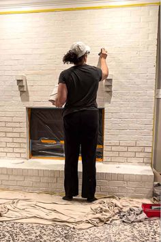 a woman standing in front of a brick fireplace with her hands on the back wall