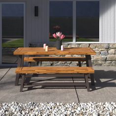 a wooden picnic table with two benches in front of it and flowers on the side