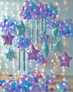 purple and blue balloons are floating in the air with streamers hanging from it's ceiling