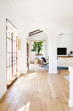 an empty living room with wood flooring and white walls on either side of the doorway