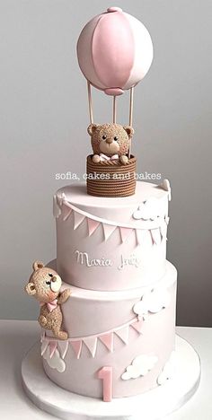 a three tiered cake with a teddy bear and hot air balloon on it's top