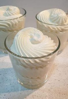 three glasses filled with whipped cream on top of a counter