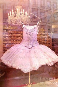 a ballerina's dress is on display in a store window with chandeliers