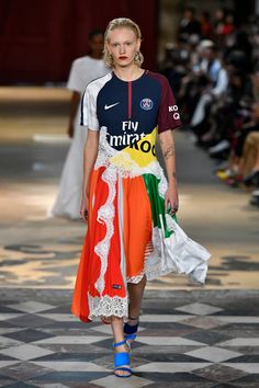 a model walks down the runway wearing an orange, white and blue dress with colorful details