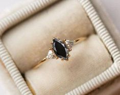 an engagement ring in a white box with gold trimmings and black diamond accents