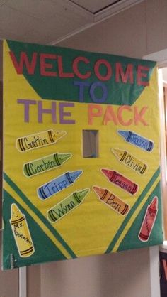 a welcome to the pack sign hanging from a wall in an office building with several crayons on it