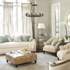 a living room filled with furniture and a chandelier hanging from the ceiling over a window