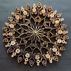 an intricate wooden wall hanging made out of rolled up wood sticks and paper machs