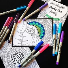 some markers and pens are on top of a coloring book