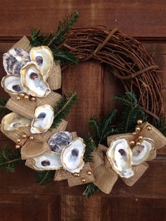 a wreath made out of seashells and burlocks on a wooden door