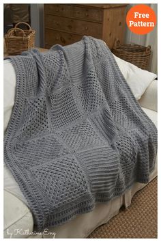 a gray knitted blanket sitting on top of a bed