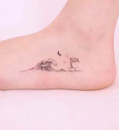 a woman's foot with a small wave and moon tattoo on the top of it