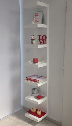 a white shelf filled with lots of books on top of a floor next to a wall