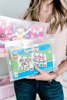 a woman holding two bags of cake making kits in front of her face and smiling at the camera