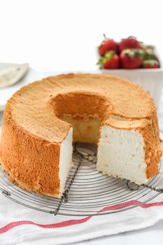 a cake that has been cut into pieces and is on a cooling rack with strawberries in the background