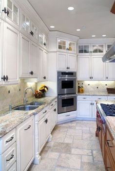 a large kitchen with white cabinets and granite counter tops, along with stainless steel appliances