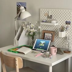 a laptop computer sitting on top of a desk next to a lamp and flower vase