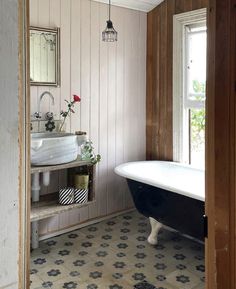 an old fashioned bathtub and sink in a bathroom with wood paneling on the walls