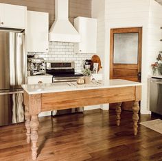 a kitchen with white walls and wooden floors has an island in front of the stove