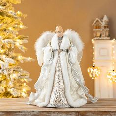 an angel figurine sitting on top of a table next to a christmas tree