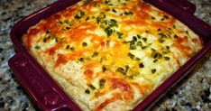 a square casserole dish with cheese and green onions on the top, sitting on a granite countertop