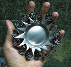 a hand holding a metal object with spirals on it's center and sides