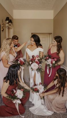 a group of women standing around each other in dresses and holding bouquets on the floor