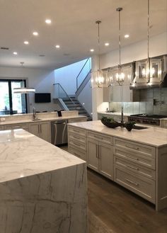 a large kitchen with marble counter tops and stainless steel appliances, along with stairs leading up to the second floor