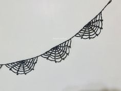 a black lace is hanging from a white wall and it looks like an intricate piece of art