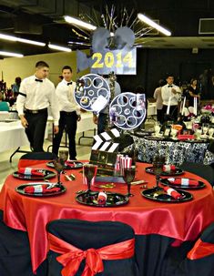 people are standing around a table with red and black plates on it that have decorations