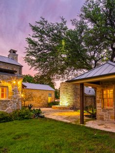 a stone house with lights on the front and side of it at dusk in texas