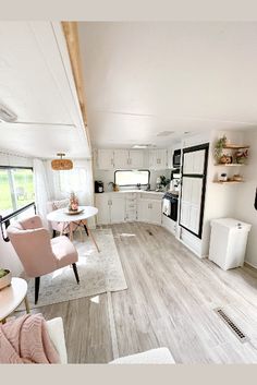 a living room filled with furniture next to a kitchen and dining room table on top of a hard wood floor