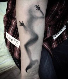 a person with a black and white tattoo on their arm that has an image of a hand coming out of it