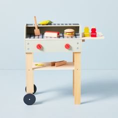 a wooden toy grill sitting on top of a white table next to a blue wall