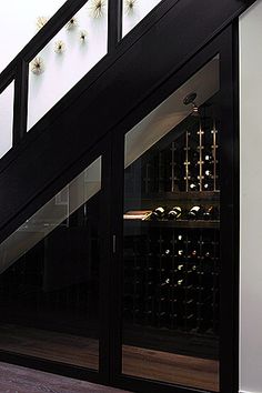 a wine cellar with lots of bottles on the wall and stairs leading up to it