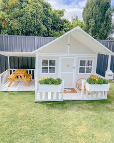 a small white shed with two planters on the porch