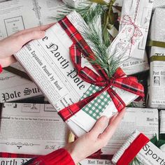 a person holding a wrapped present in front of many newspaper pages with christmas decorations on them