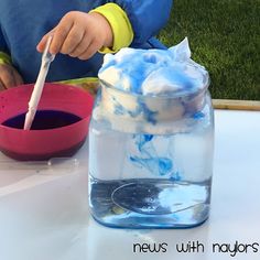 a young child is sitting at a table with blue and white food in a jar