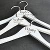 four pairs of white wooden clothes hangers with names on them