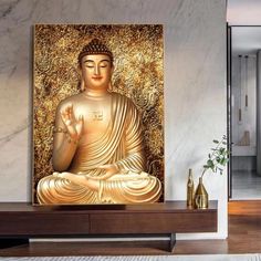 a golden buddha statue sitting on top of a wooden table in front of a painting