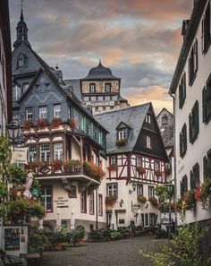 an old european street with flowers on the balconies and buildings in the background