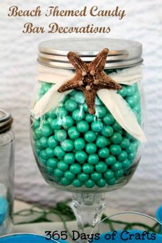 a glass jar filled with green and white candies next to a starfish on the beach