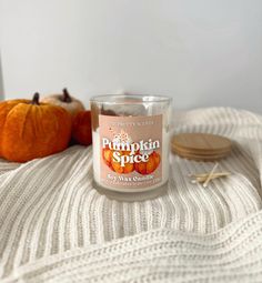 a pumpkin spice candle sitting on top of a white blanket