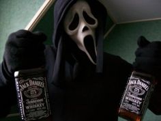 a person in a hooded jacket holding two bottles of jack daniels whiskey with a ghost mask on