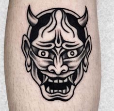 a black and white image of a demon mask on the leg, with an evil look