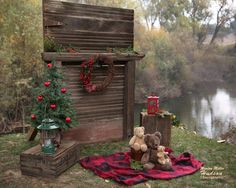 a teddy bear sitting on a blanket next to a christmas tree and mailbox in the grass